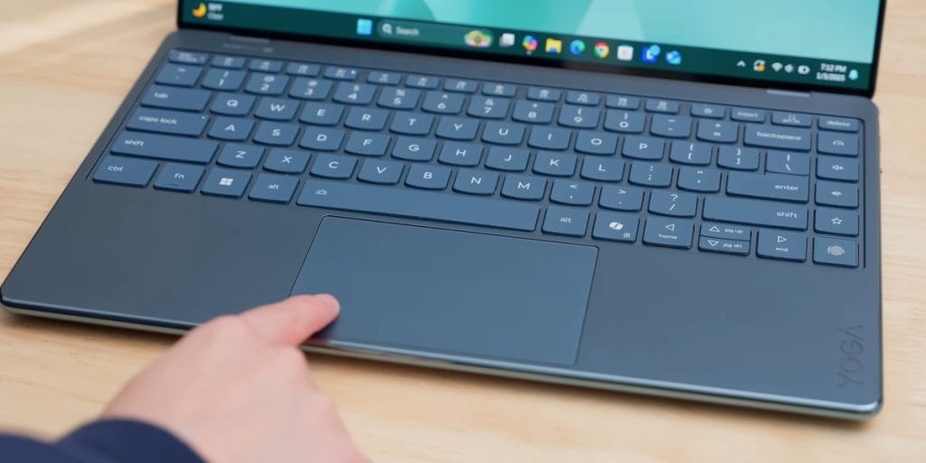 A close-up of a hand using the spacious trackpad on the Lenovo Yoga Slim 9i laptop.